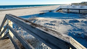A wooden boardwalk leading to a beach with a wooden pier in the background. - Inlet Holiday - Creekfront in Garden City Beach (Garden City Beach)