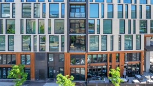 A modern multi-story building with large windows, a ground-level café, and a visible parking area. - Perfect Dntwn Retreat- Convention Cntr- Amenities! (Salt Lake City)