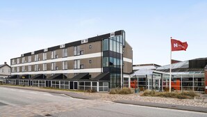 A modern building with a glass facade, a red flag with a white heart, and a sign reading "FANØBAD." - 2 bedroom stunning apartment in Fanø (Fanø)