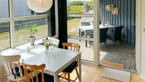 A dining area with a white table and chairs, a potted plant, and a bottle of wine. - 2 bedroom stunning apartment in Fanø (Fanø)