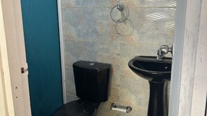 A small bathroom with a toilet, a sink, and a towel rack. - Punta Arena EcoHostal & EcoFit (Cartagena)