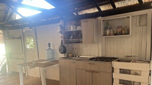 A rustic kitchen with wooden cabinets, a gas stove, and a large water dispenser. - Punta Arena EcoHostal & EcoFit (Cartagena)