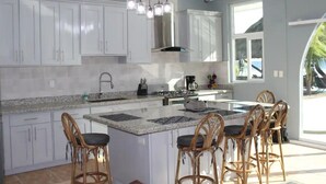 A modern kitchen with white cabinets, a granite countertop, and a central island with bar stools.