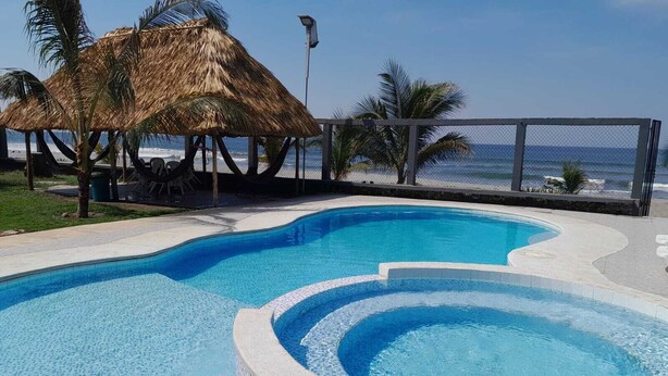 A swimming pool with a curved design, surrounded by a stone border and a tiled edge.