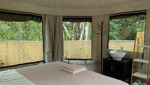 Un dormitorio con cama, una mesita de noche con lavamanos y vistas al exterior.