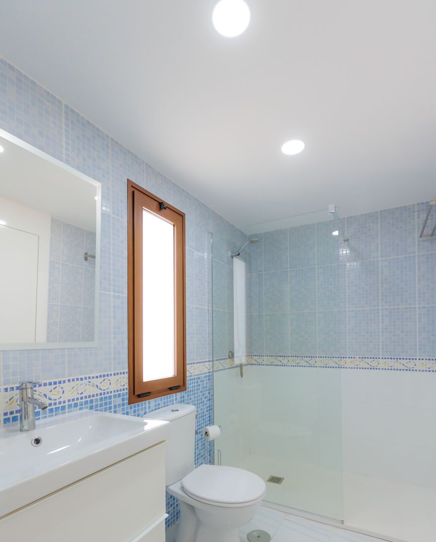 Une salle de bain avec un lavabo blanc, des toilettes et une douche à parois de verre.