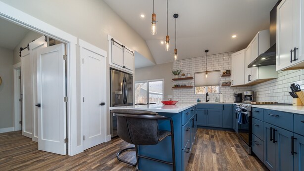 A modern kitchen with a central island, blue cabinets, and a stainless steel refrigerator. - Modern Bungalow in the Heart of Fruita (Fruita)