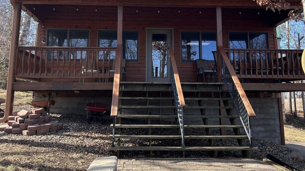 A two-story wooden house with a porch, a stone birdbath, and a brick fire pit. - Lake Home property (Luck)