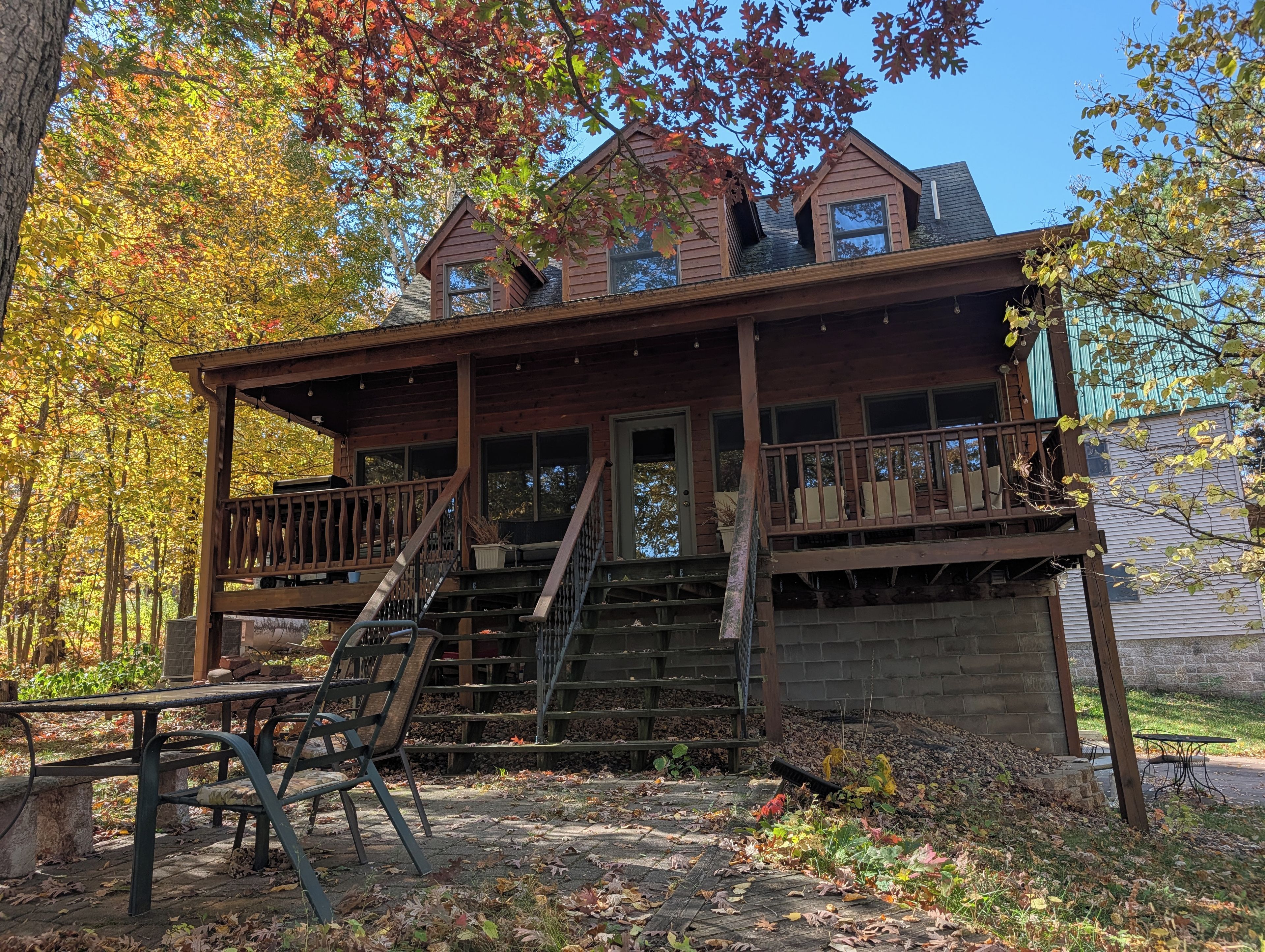 A wooden cabin with a porch, a staircase, and a small outdoor seating area.
