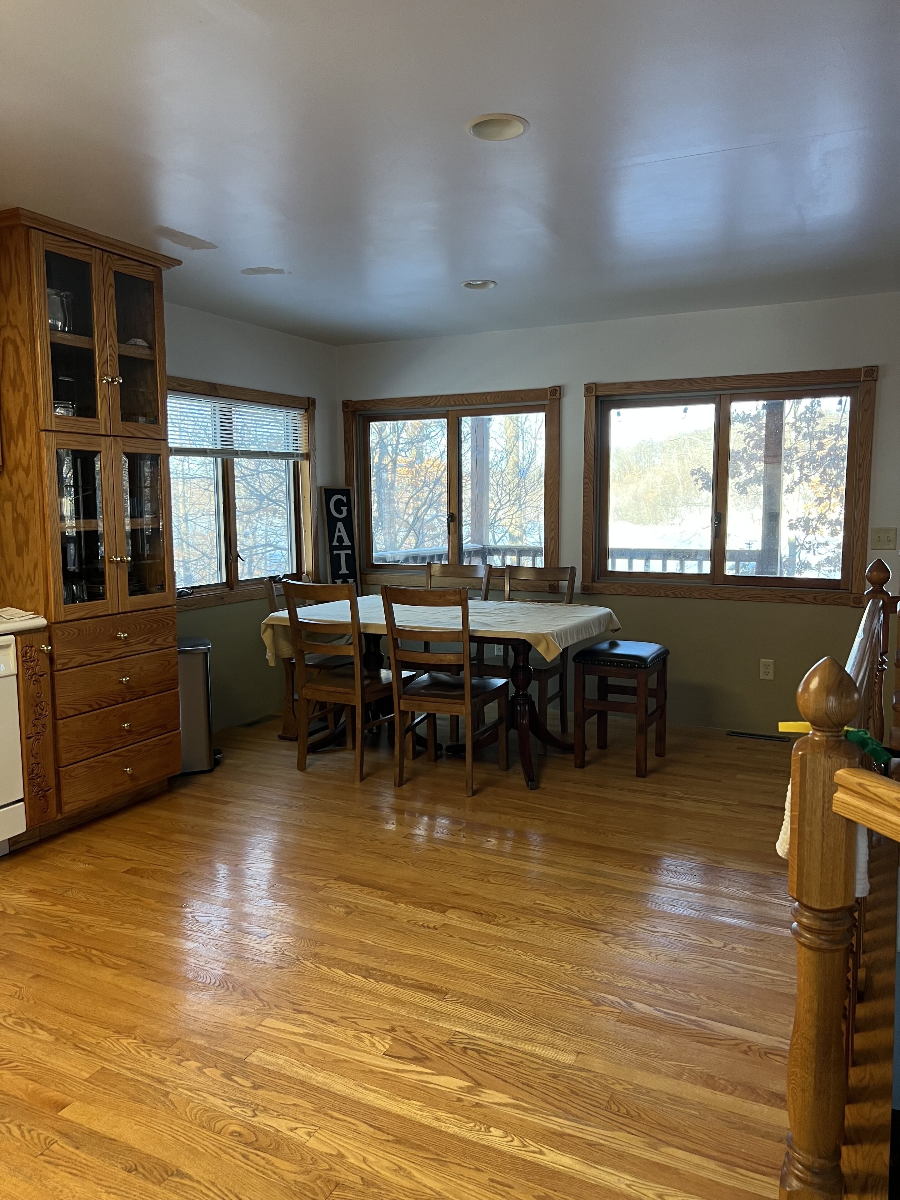 A spacious kitchen with wooden cabinets, a dining table, and large windows.