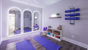Ein Zimmer mit einem großen Spiegel, Yogamatten, einem Regal mit Körben und einem Wandhalterung für Yogamatten.