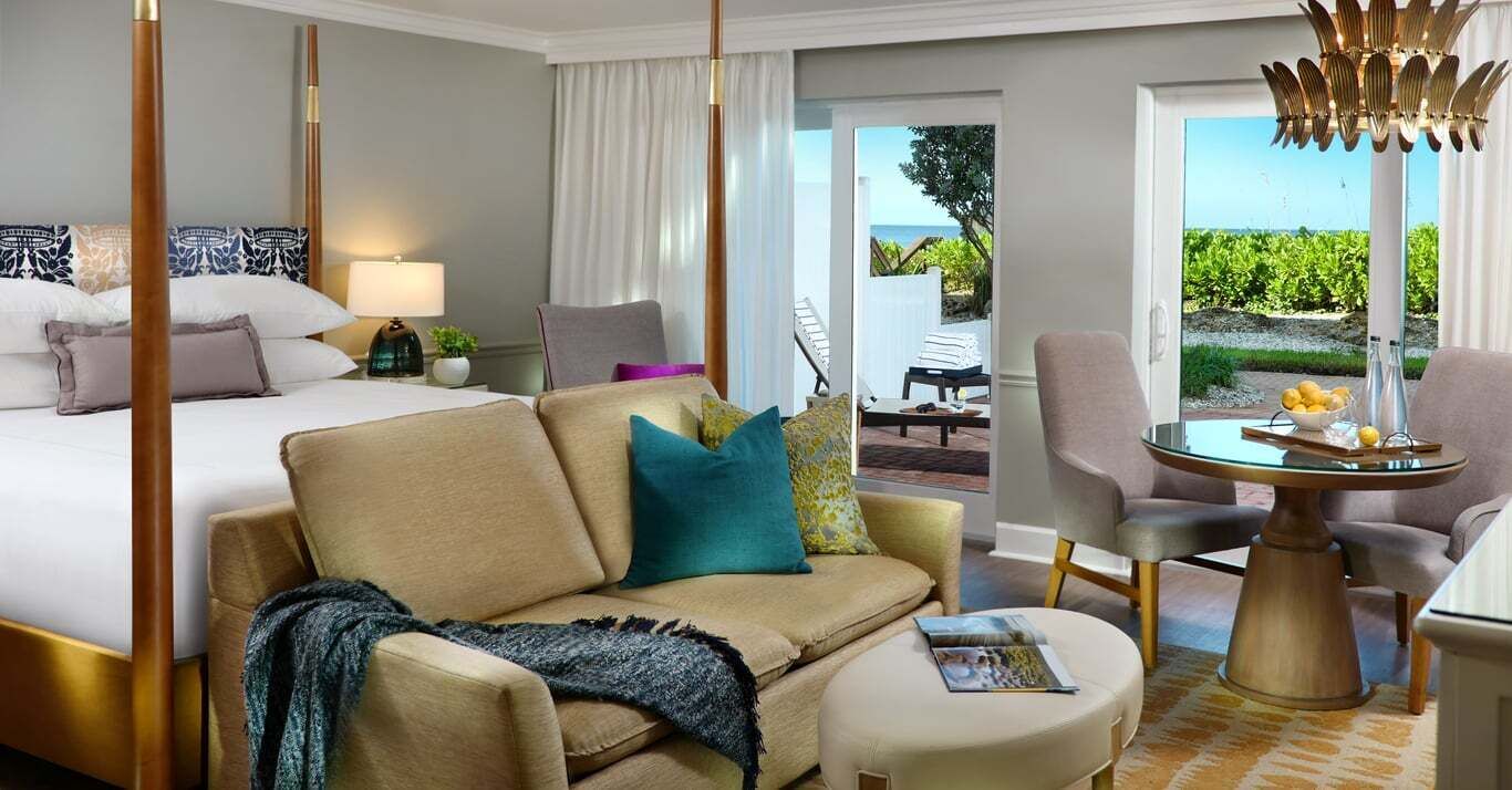 A hotel room with a bed, a sofa, a coffee table, and a view of the outdoors.