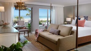 Une chambre d’hôtel avec un lit, un canapé, un bureau et vue sur la plage.