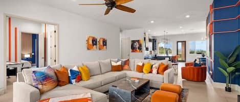 A modern living room with a sectional sofa, a coffee table, and a ceiling fan.