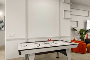 Quarto moderno com mesa de pebolim, sofá e planta.