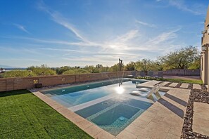 Ein rechteckiger Swimmingpool mit klarem Wasser, umgeben von einer Ziegelmauer und einer Rasenfläche.