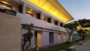 A modern building with multiple balconies, a well-maintained lawn, and a series of benches along the walkway. - Kuta Living (Kuta)