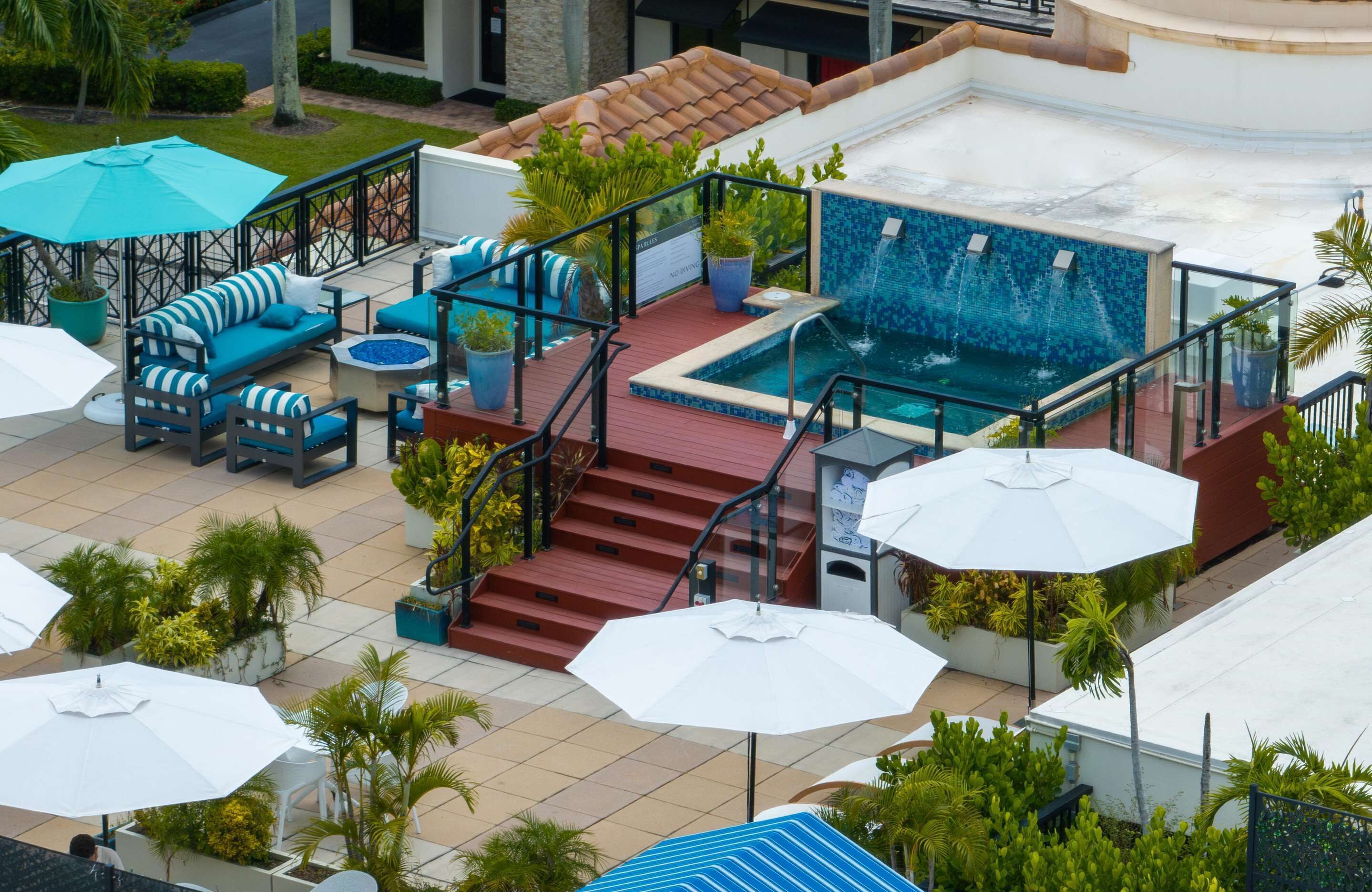 A rooftop pool area with a jacuzzi, outdoor seating, and a staircase leading to the pool.