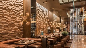 Un restaurant moderne avec des banquettes en cuir, un mur décoré de motifs en briques et un présentoir à vin.