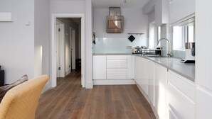 Een moderne keuken met witte kasten, een houten vloer en een roestvrijstalen afzuigkap.