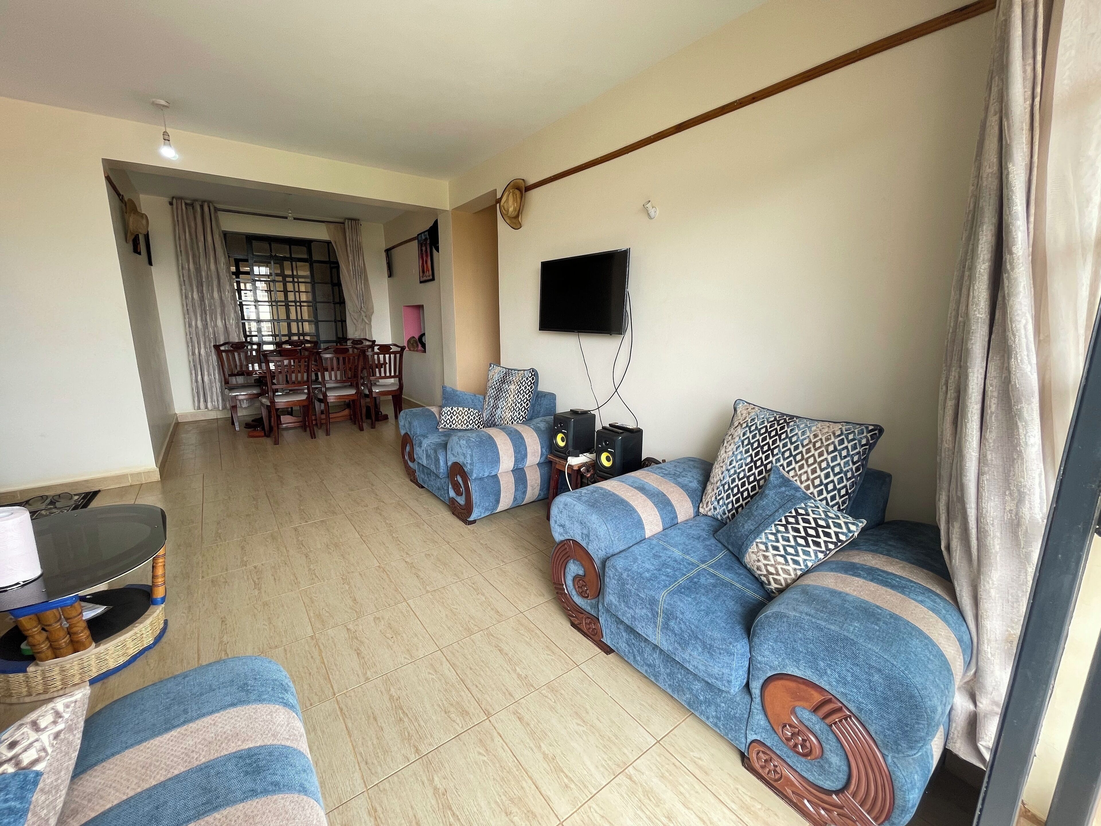 A living room with a sofa set, a television, and a dining area with chairs and a table.