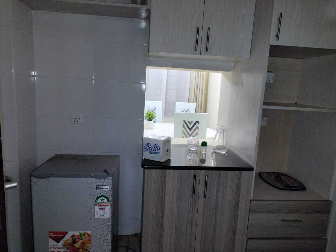 Una cocina compacta con refrigerador, un lavamanos y armarios.