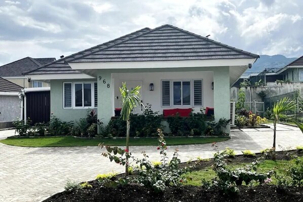 Eingeschossiges Haus mit Ziegeldach, Veranda und gepflegtem Garten.