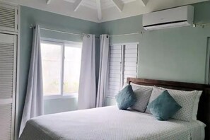 Ein Schlafzimmer mit Bett, Vorhängen, einer Klimaanlage und einem Fenster.