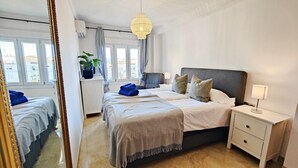 Un dormitorio con cama, mesitas de noche, lámpara colgante y un espejo grande.