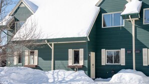 A two-story house with a snow-covered roof and a front porch.
