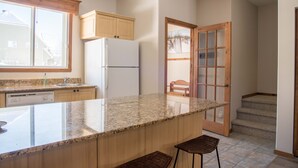A kitchen with granite countertops, wooden cabinets, a built-in dishwasher, and a refrigerator.