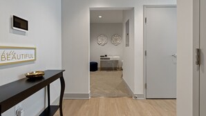 En hall med ett mörkt träbord, en väggmonterad tv och en dekorativ skylt.