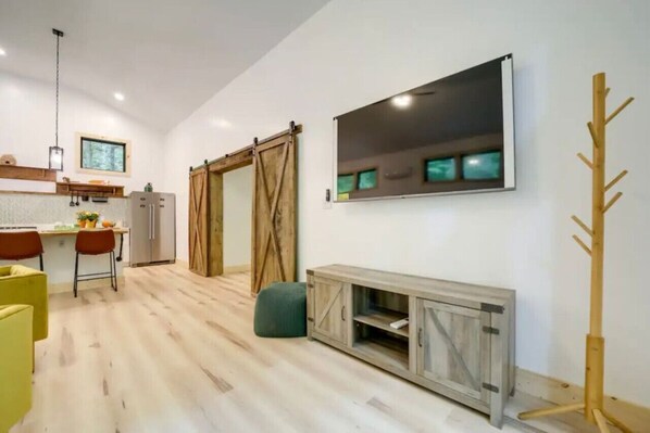 A modern kitchen with a dining area, wooden flooring, and a large mirror on the wall.
