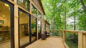 A wooden deck with glass doors leading to a room, surrounded by a forest. - 🔥 Fall Flash Sale –15% Off Waterfall deal Spacious 3 Bedroom Cabin Plus One Bedroom Beekeeper Cabin Waterfalls AWD or 4WD recommended (Hot Springs)