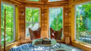 A cozy cabin with large windows, wooden walls, and a round table with books. - 🔥 Fall Flash Sale –15% Off Waterfall deal Spacious 3 Bedroom Cabin Plus One Bedroom Beekeeper Cabin Waterfalls AWD or 4WD recommended (Hot Springs)
