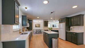 A modern kitchen with dark cabinets, a central island, and pendant lighting.