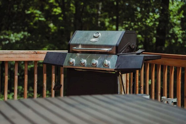 Una parrilla sobre una terraza de madera con barandilla de metal.