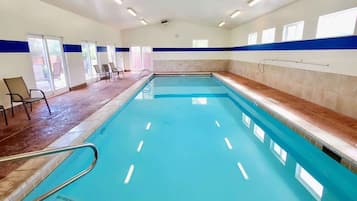 An indoor swimming pool with a 3ft 0in depth marker, surrounded by chairs and a blue stripe on the walls.