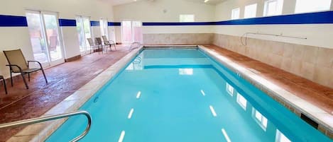 An indoor swimming pool with a 3ft 0in depth marker, surrounded by chairs and a blue stripe on the walls.