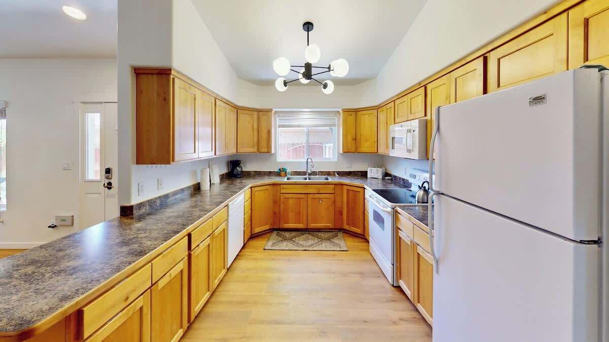 A kitchen with wooden cabinets, a granite countertop, a white refrigerator, and a central island.