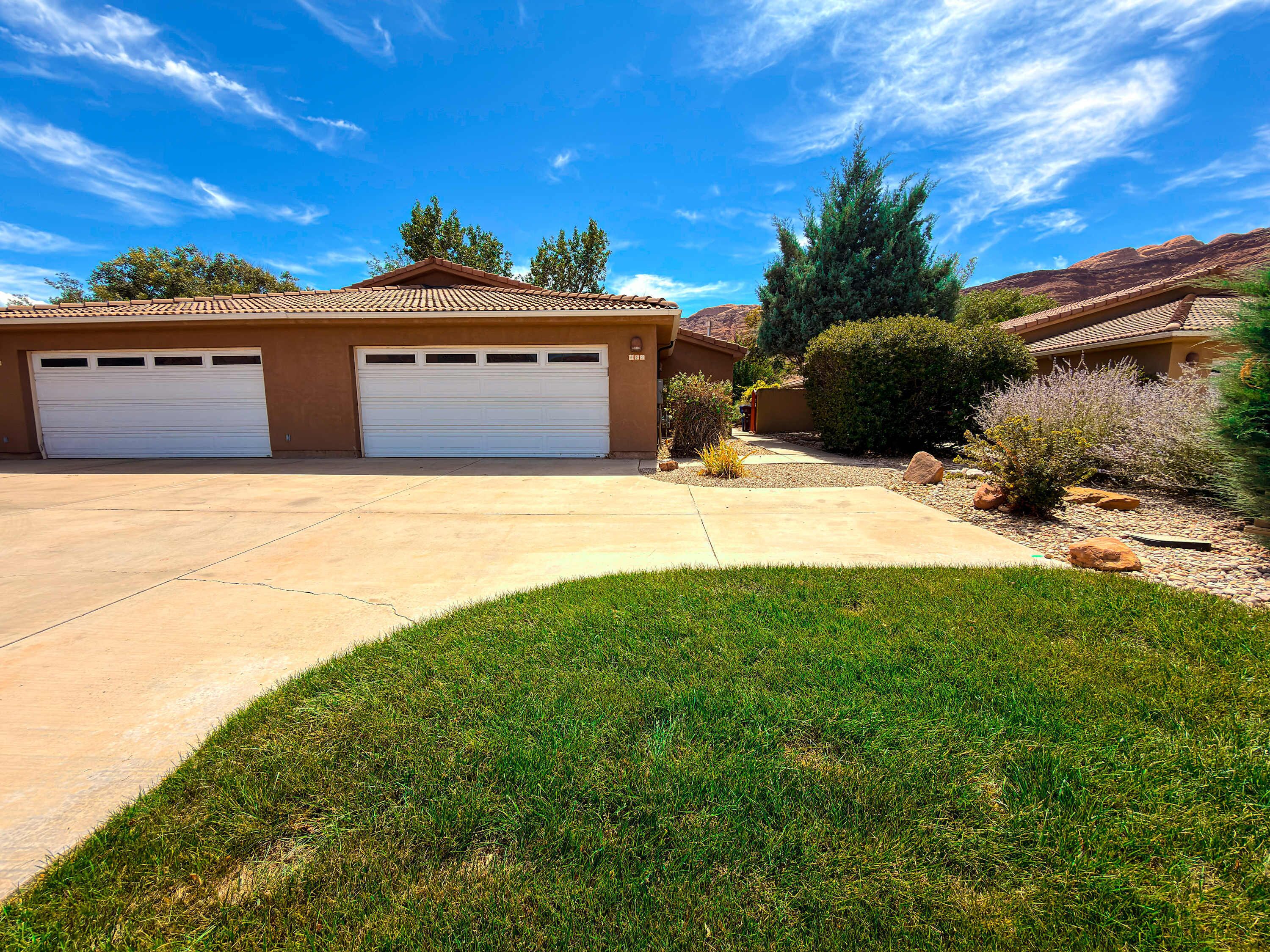 A residential property with a garage, driveway, and landscaped yard.