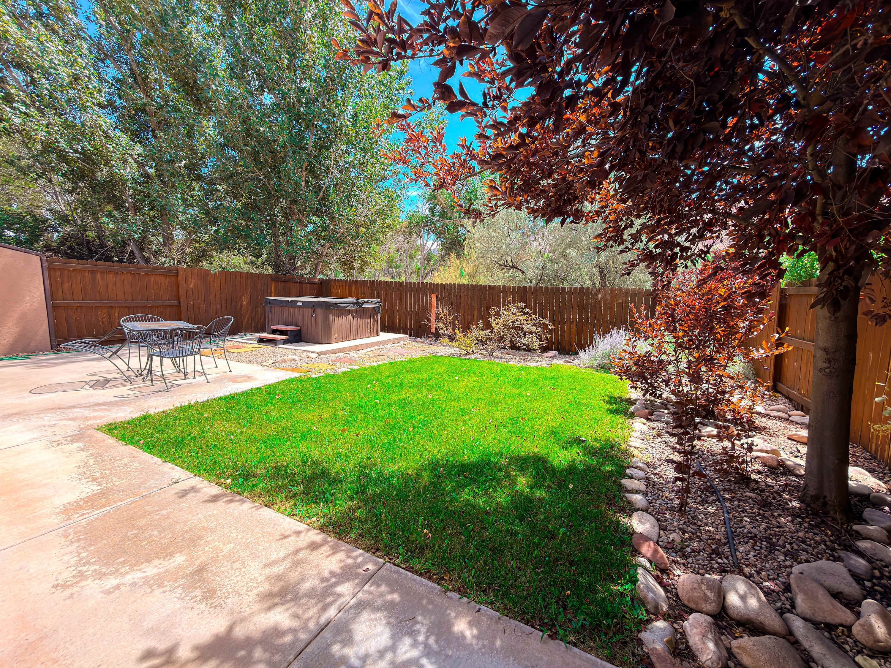 A backyard with a hot tub, patio furniture, and a well-maintained lawn.