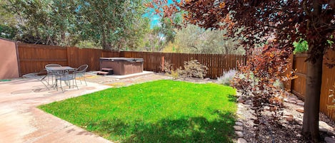 A backyard with a hot tub, patio furniture, and a well-maintained lawn.