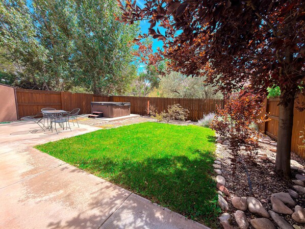 A backyard with a hot tub, patio furniture, and a well-maintained lawn.