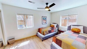 A bedroom with a bed, a bedside table, a ceiling fan, and a window.