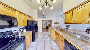 A kitchen with wooden cabinets, a black refrigerator, a stove, and a dishwasher.