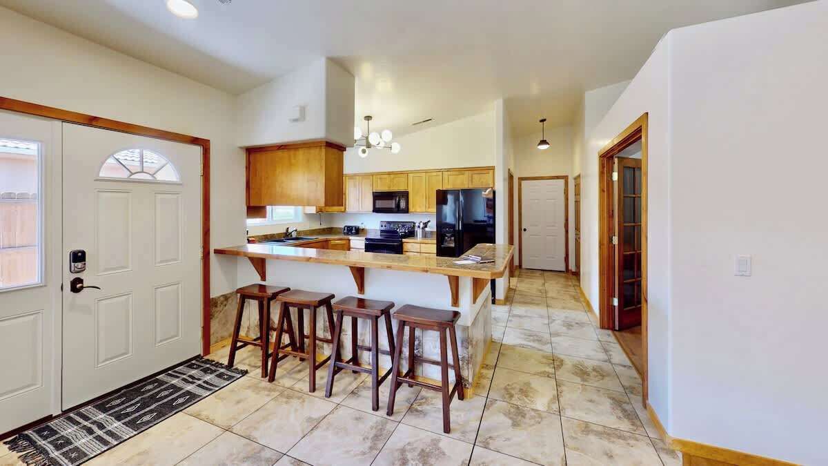 A modern kitchen with a central island, wooden bar stools, and built-in appliances.