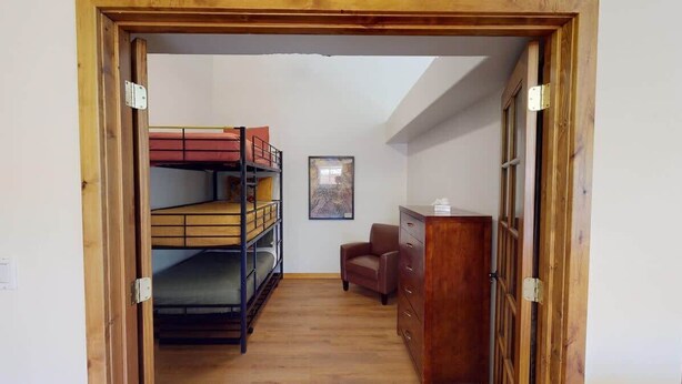 Una habitación con literas, una silla, un aparador y un cuadro en la pared.