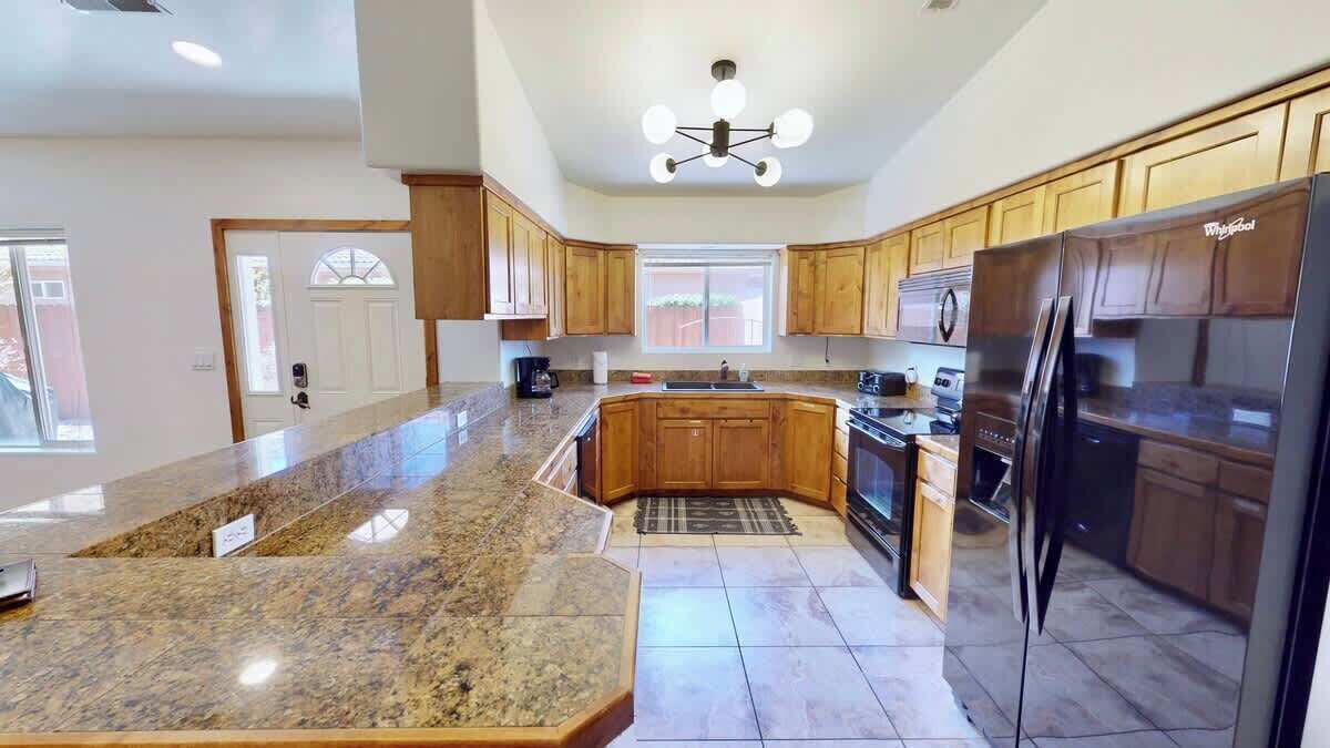 A kitchen with granite countertops, wooden cabinets, a stainless steel refrigerator, and a built-in oven.