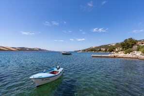 Um corpo d'água calmo com barcos, céu claro e paisagem montanhosa ao fundo.
